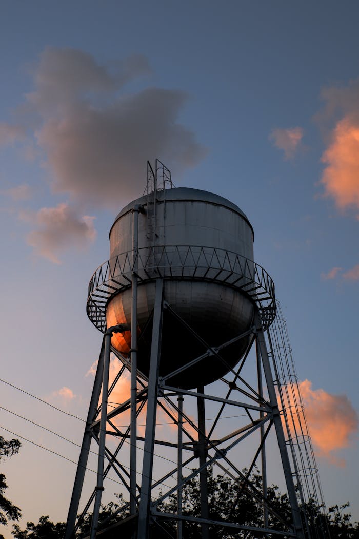 Water tower under cloudy sky at sunset